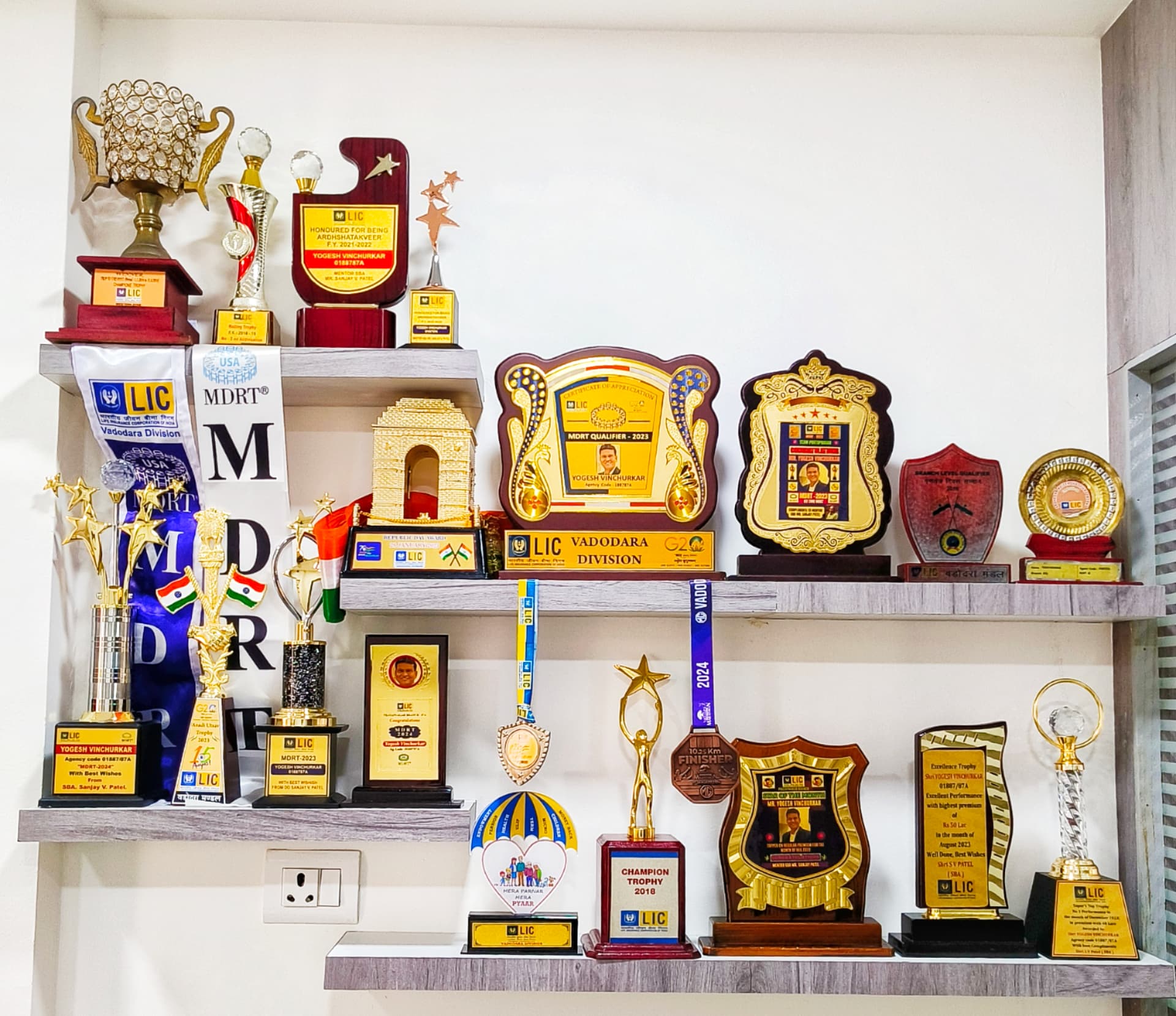 Smart Investments office wall with LIC and MDRT trophies, certificates and awards